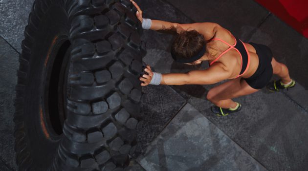 Strong sporty woman flipping tyre