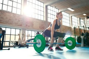 Focused young woman lifting weights in a gym